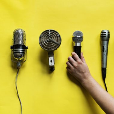 Hand holding microphone isolated on background